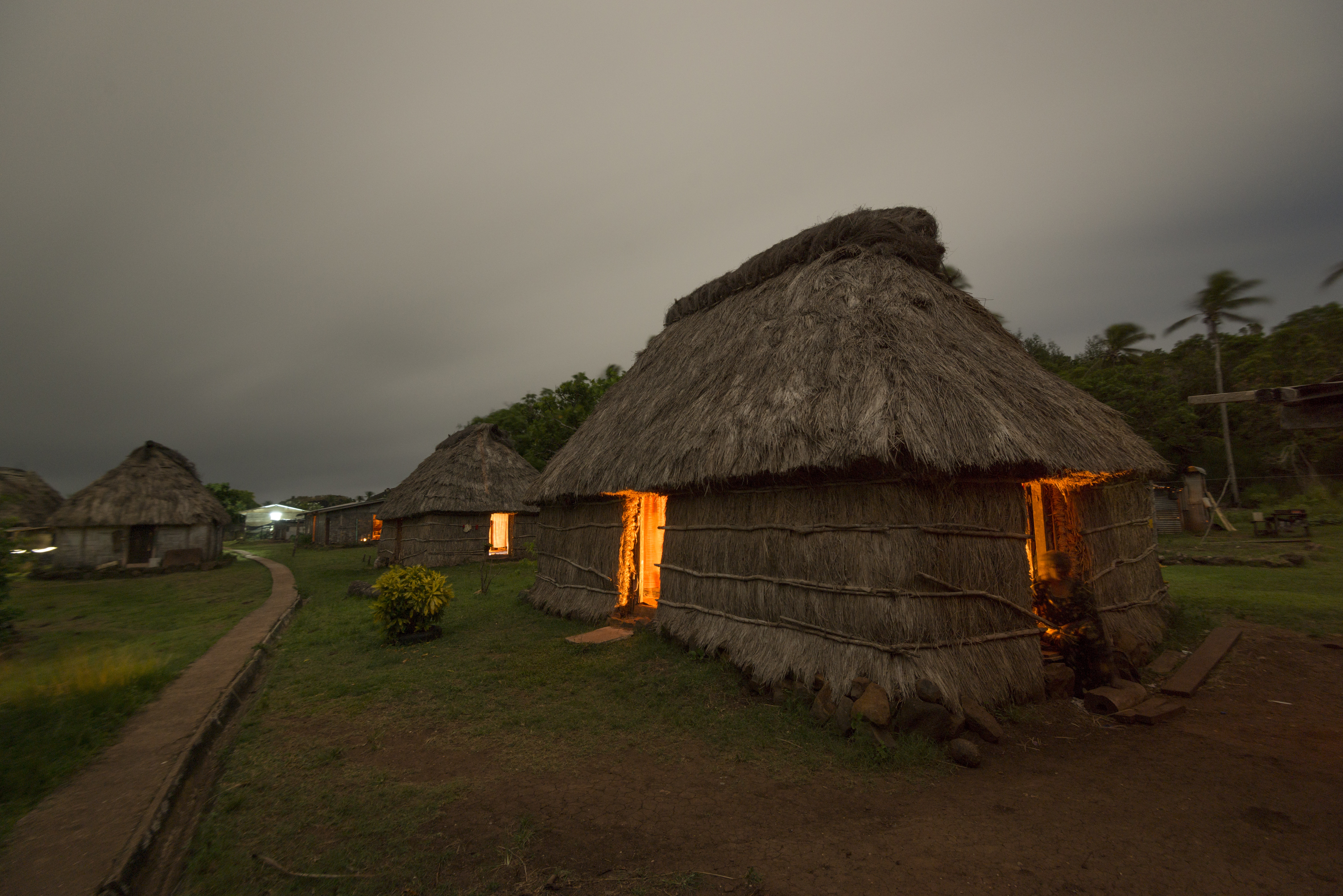 Night time shot of a traditional Fijian bure or homes made with thatched roofs and natural material walls.